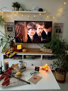 a flat screen tv sitting on top of a white table next to potted plants