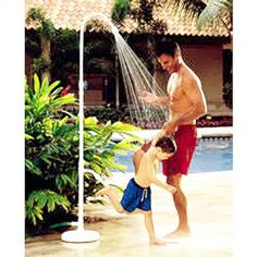 a father and son playing in a pool sprinkled with water from a hose