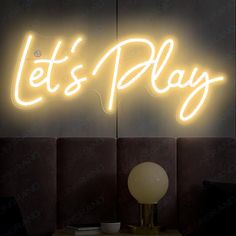 there is a neon sign that says let's play on the side of a wall