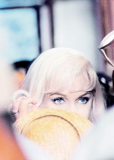 a woman with blonde hair and blue eyes wearing a straw hat looking over her shoulder