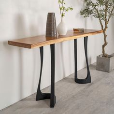 a wooden table with two vases sitting on it's sides next to a plant