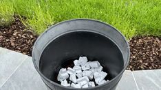 a bucket filled with ice cubes sitting on top of a cement floor next to grass