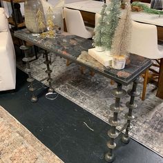 a glass table topped with christmas trees on top of a carpeted floor next to white couches