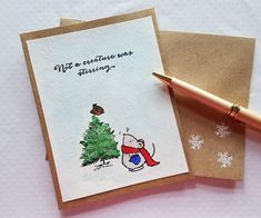 a card with a christmas tree on it next to a pen