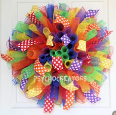 a colorful mesh wreath with polka dots and ribbons hanging on the front door to welcome visitors