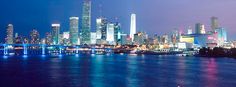 the city skyline is lit up at night with lights reflecting in the water and skyscrapers