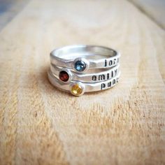 three different rings with words on them sitting on a wooden surface, one is silver and the other is gold