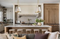 a kitchen island with stools in front of it and lights hanging from the ceiling