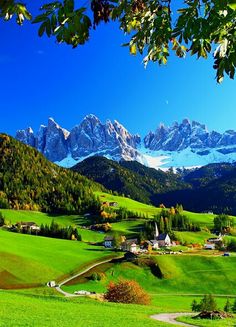 the mountains are covered in snow and green grass, with small houses on each side