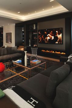 a living room with black furniture and a flat screen tv mounted on the wall above it