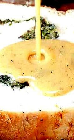 a close up of a sandwich with cheese and sauce being poured on it to the side