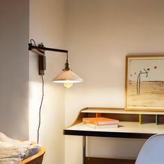 a desk with a lamp and some books on it in the corner of a room