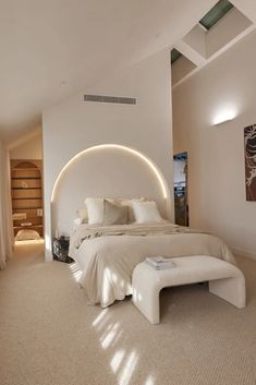 a large white bed sitting inside of a bedroom next to a tall wooden shelf on the wall