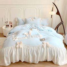 a bed with blue sheets and white ruffled bedspread on top of it