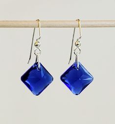 "- Dazzling Majestic Blue Earrings in Swarovski Faceted 5/8\" Squares in Diamond Layout with 925 Sterling Silver Angular Hooks. See Photos #1-2. - Swarovski Faceted Square Shaped Crystal in \"Majestic Blue\" Shade could be called Cobalt, Royal or Electric Blue.   - 925 Sterling Silver Triangle Jump Rings connect the Earring to the Hooks. - 925 Sterling Silver Angular Hook Ear Wire with 3mm Ball Ends.  - 925 Sterling Silver Posts (Studs) with 4mm Ball Ends and Backs upon request at no added cost. Blue Sterling Silver Crystal Earrings For Formal Events, Blue Sterling Silver Crystal Earrings For Formal Occasions, Blue Sterling Silver Pierced Crystal Earrings, Nickel-free Blue Crystal Earrings For Formal Occasions, Blue Sterling Silver Crystal Earrings For Pierced Ears, Nickel-free Blue Crystal Earrings, Nickel Free Blue Crystal Earrings, Blue Round Sterling Silver Crystal Earrings, Classic Blue Nickel-free Earrings