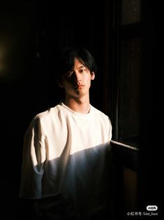 a man standing next to a window in the dark