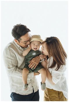 a man and woman are holding a baby in their arms as they smile at each other