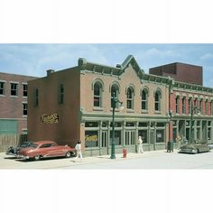 an old building with cars parked on the side of it and people walking around in front