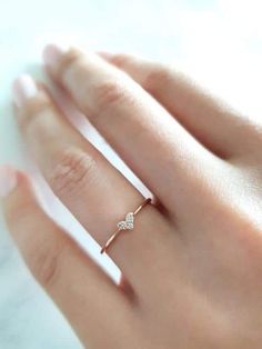 a woman's hand wearing a gold ring with two small diamonds on the band