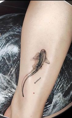 a small tattoo on the leg of a woman's foot with a fish in it