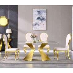 a dining room table with white chairs and gold accents