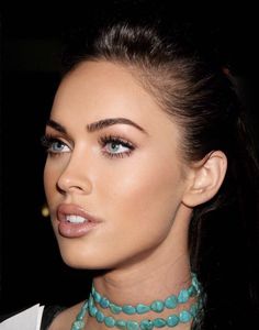 a close up of a woman wearing a necklace and choker with blue eyeshadow