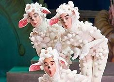 three people in sheep costumes on stage with one holding the other's leg up