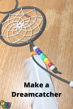 a wooden table topped with a white and black dream catcher next to a rainbow bead necklace