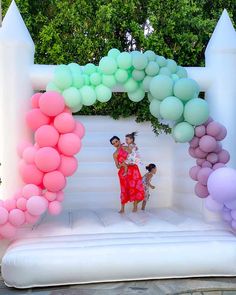 two women standing in front of an arch made out of balloons