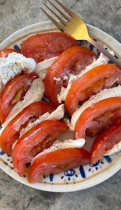 a plate with sliced tomatoes and cream cheese on it next to a knife and fork