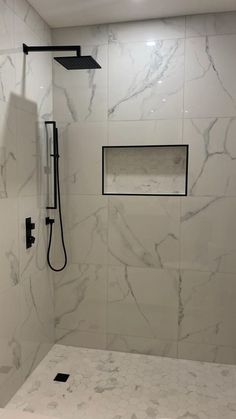 a bathroom with white marble walls and flooring, including a walk - in shower