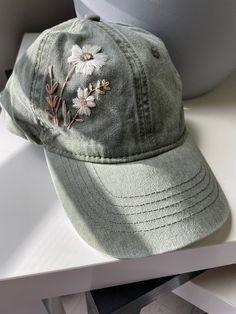 a green hat with embroidered flowers on it