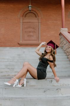 a woman in a graduation cap and gown sitting on the steps with her legs crossed