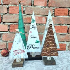 three small wooden christmas trees sitting on top of a table next to a brick wall