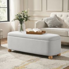 a living room with white furniture and flowers on the coffee table