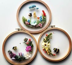 three embroidery hoop frames with flowers and bees on them