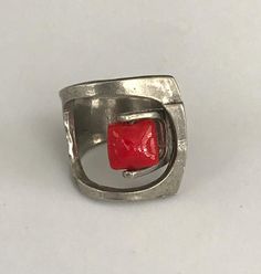 This eye catching sculptural ring is kinetic in that the bright red square bead swivels! The shape reminds me of the old fashioned buckle ring. The face of this ring is 1" at its longest. The red square bead is faceted. The ring is marked Anne Marie Chagnon (the mark is a bit faded). it is size 7 1/2 - 8. It is in very good vintage condition. Please see all photos for details, as well as, condition.Thank you for looking! Modern Red Ring Jewelry, Hand Cast Modernist Jewelry For Gifts, Modernist Hand-cast Jewelry For Gifts, Contemporary Red Jewelry For Gifts, Modernist Hand Cast Jewelry As Gift, Contemporary Square Jewelry For Gifts, Contemporary Red Jewelry For Gift, Contemporary Red Jewelry As A Gift, Handmade Square Red Jewelry