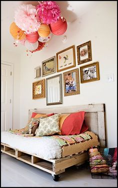 an image of a bedroom with pictures on the wall and below it is a bed made out of pallets