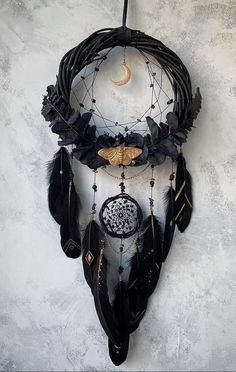 a black dream catcher with feathers hanging from it's side and a crescent moon