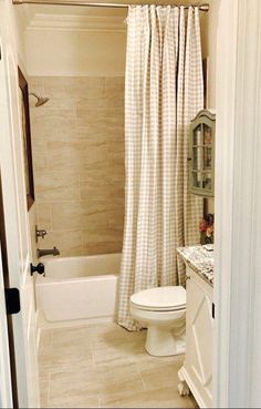 a white toilet sitting next to a bath tub in a bathroom under a shower curtain