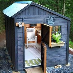 a small shed with an open door on the side and a chair in it's doorway