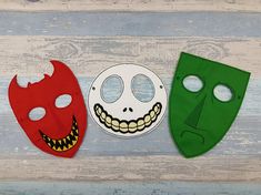 three masks with faces painted on them sitting next to each other