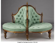 an antique style couch with green upholstered back and foot rests against a gray background