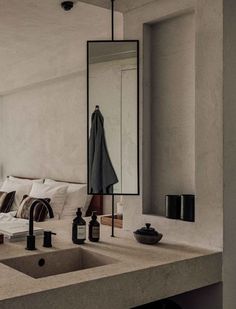 a bathroom sink sitting under a large mirror next to a counter top with bottles on it