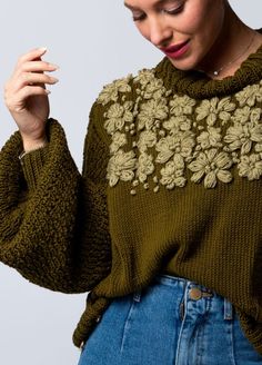 a woman wearing a green sweater with flowers on it