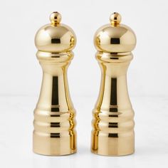 two golden pepper mills sitting side by side