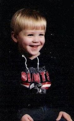 a young boy sitting on the ground smiling