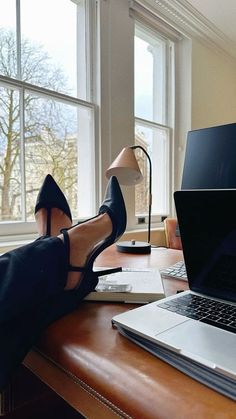 a woman in high heels sitting at a desk with her feet up on a laptop