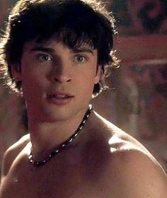 shirtless young man with no shirt on looking at the camera while wearing a chain around his neck