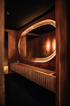 a bathroom with an oval mirror above the sink and two sinks below it in front of a wall mounted faucet